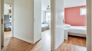 Et moderne hotelværelse med trægulv, en seng, et skrivebord og et vindue med gardiner.