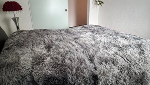 A bedroom with a large fluffy grey bed, a sliding door, a mirror, and a red flower vase. - Red Silence I Design Suite near Koblenz I Experience, Not Standard (Bendorf)