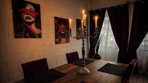 A dining area with a brick wall, a wooden table, red cushions, and a candelabra with candles. - Red Silence I Design Suite near Koblenz I Experience, Not Standard (Bendorf)