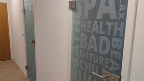 Un couloir avec une porte en verre sur laquelle figurent des mots tels que « SPA », « DÉTENTE » et « BIEN-ÊTRE ».