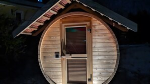 Une petite structure circulaire en bois, dotée d’une porte et d’une fenêtre, et éclairée par des lumières.