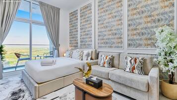 Une chambre d’hôtel moderne dotée d’un grand lit, d’un canapé, d’une table basse et offrant une vue sur la campagne.