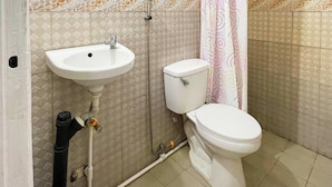 Une salle de bain avec un lavabo, des toilettes et une douche, le tout de couleur blanche.