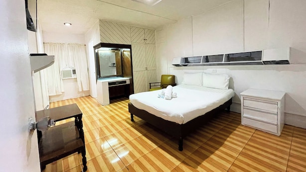 Une chambre d’hôtel comprenant un lit, une table de chevet, une commode et un miroir.