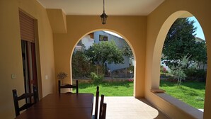 Ein Essbereich mit Tisch und Stühlen, einem Bogenfenster und Blick auf Garten und Gebäude.