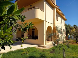 A two-story building with a curved facade, arched windows, and a balcony. - Sardinian Wind House, vacation home South Sardinia 600 m from the sea (La Maddalena)