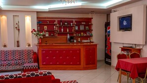 Un hall d’hôtel avec un canapé rouge, une table rouge, un téléviseur et un distributeur automatique de Pepsi.