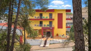A multi-story building with a yellow facade, balconies, and a ground-level entrance.