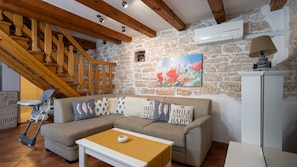 A cozy living room with a stone wall, wooden staircase, and a sofa with decorative pillows. - Villa Katarina by Villas Guide (Barban)