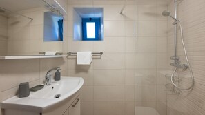 Ein modernes Badezimmer mit Waschbecken, Spiegel, Handtuchhalter, Dusche und einem kleinen Fenster.