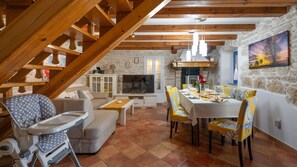 A cozy living room with a dining area, wooden beams, stone walls, a TV, and a painting. - Villa Katarina by Villas Guide (Barban)