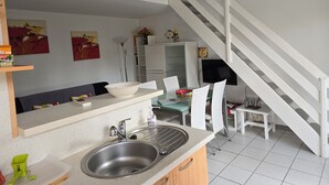 Eine moderne Küche mit Spüle, weißen Stühlen und einer Treppe.