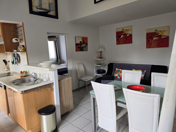 Une cuisine compacte avec un évier, un petit coin repas comprenant une table et des chaises, et un canapé.