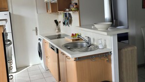 Eine kompakte Küche mit integriertem Geschirrspüler, Spüle und kleiner Arbeitsfläche.