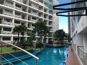 Ein modernes Hotelinterieur mit Schwimmbad, mehreren Balkonen und Zimmerpflanzen.