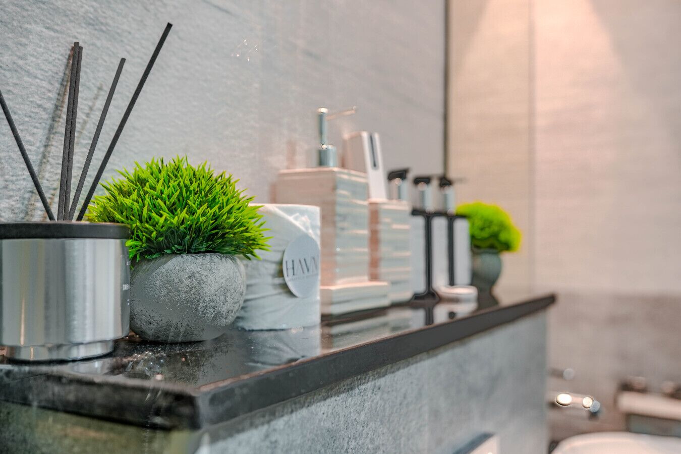 A bathroom counter with a potted plant, a towel, and toiletries.