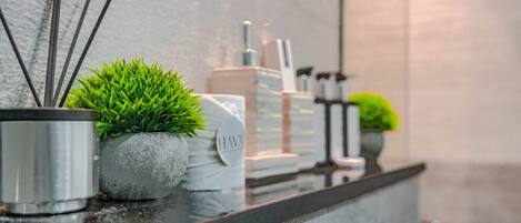 A bathroom counter with a potted plant, a towel, and toiletries.