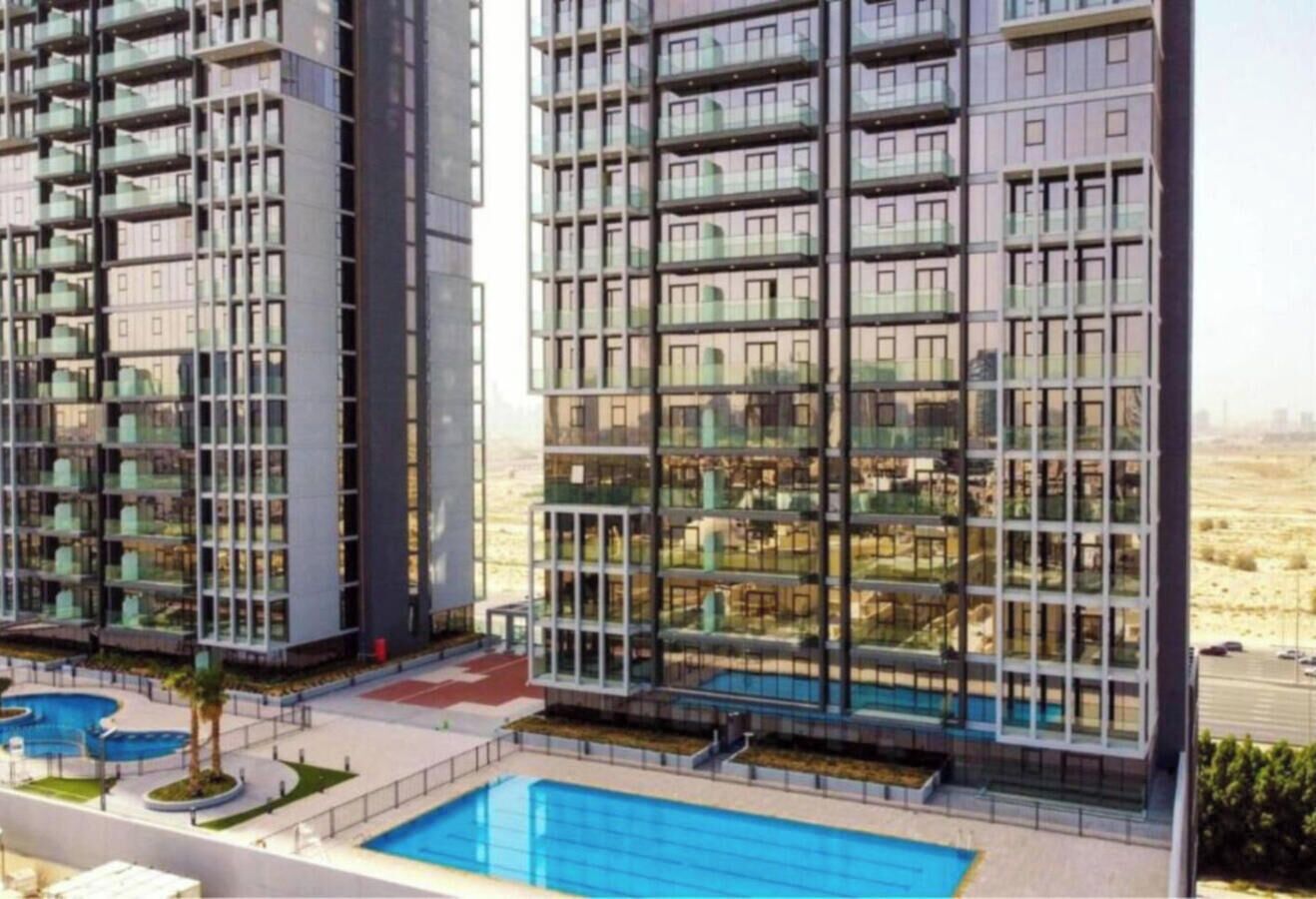 A high-rise residential building with multiple balconies, a swimming pool, and a landscaped area.