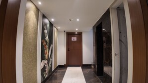 A hallway with a marble floor, a wooden door with a 'No Entry' sign, and a wall with a large floral mural. - Aarambh by The Sky Imperial Indore (Indore)