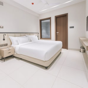 Ein modernes Hotelzimmer mit einem großen Bett, einem Nachttisch, einem Kleiderschrank und einem Badebereich.