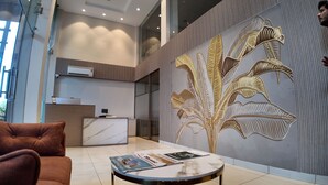 A modern interior with a marble reception desk, a plush brown sofa, and a decorative wall with a leaf pattern. - Aarambh by The Sky Imperial Indore (Indore)