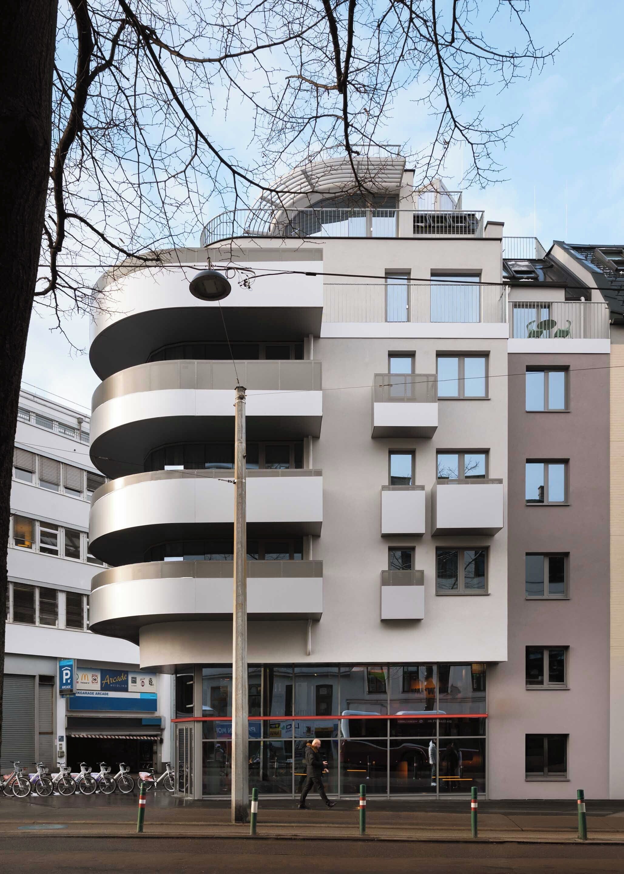 Ein mehrstöckiges Gebäude mit moderner Architektur, mit Balkonen und großen Fenstern.