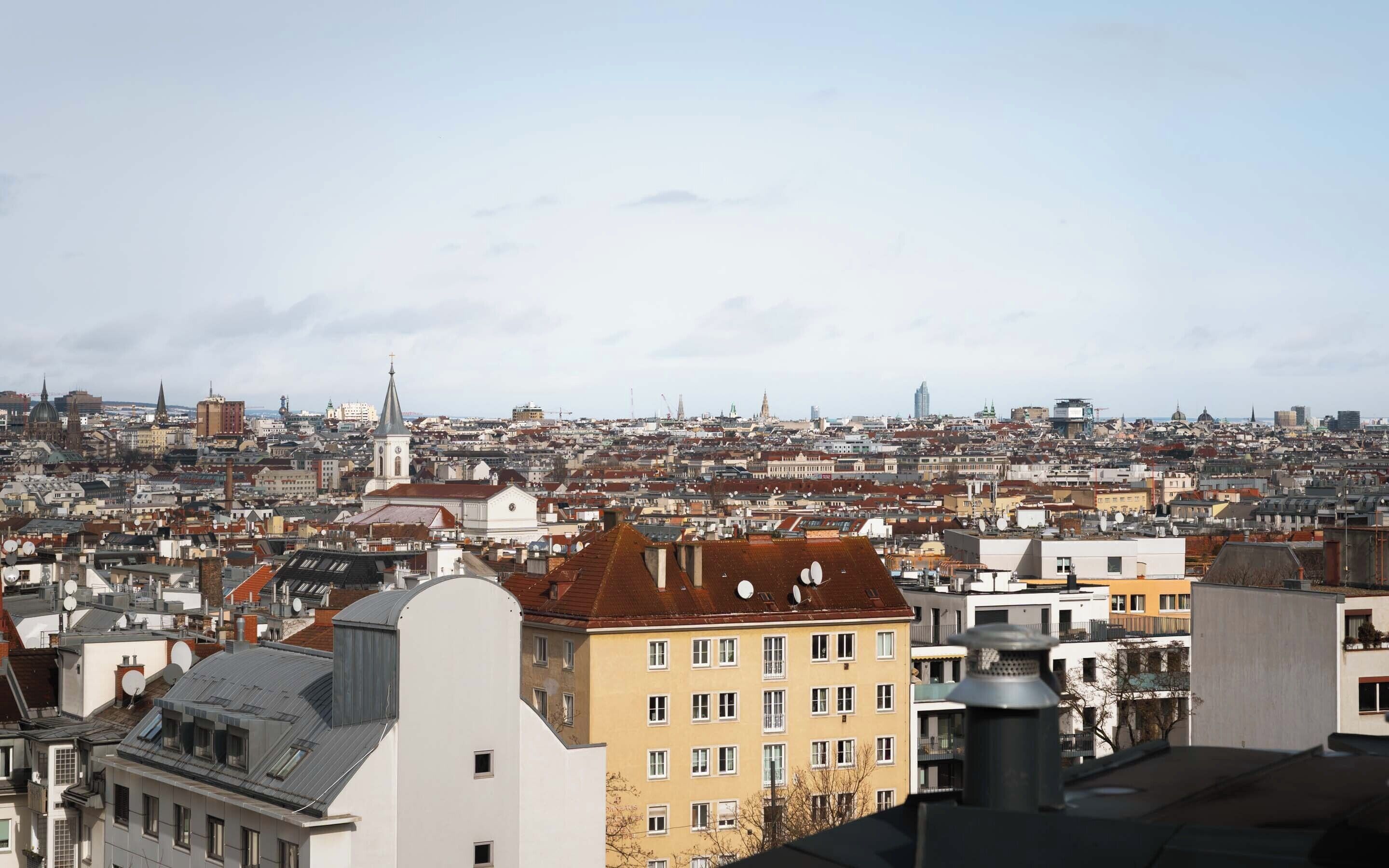 Un paysage urbain caractérisé par un clocher d’église imposant, des immeubles denses et un mélange de bâtiments résidentiels et commerciaux.