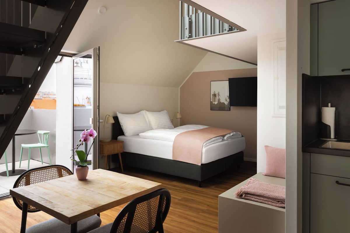 Ein modernes Schlafzimmer mit Bett, Schreibtisch und Stuhl. Eine Treppe führt zu einer oberen Ebene.