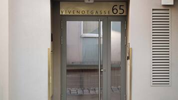 Una entrada de edificio con puerta de cristal, un letrero que dice "limehome" arriba y la dirección "WIVENOTGASSE 65".