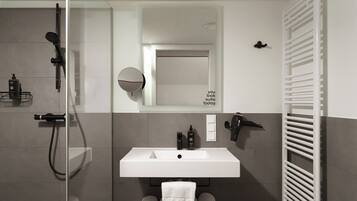 A modern bathroom with a glass shower enclosure, a white sink, and a towel rack.