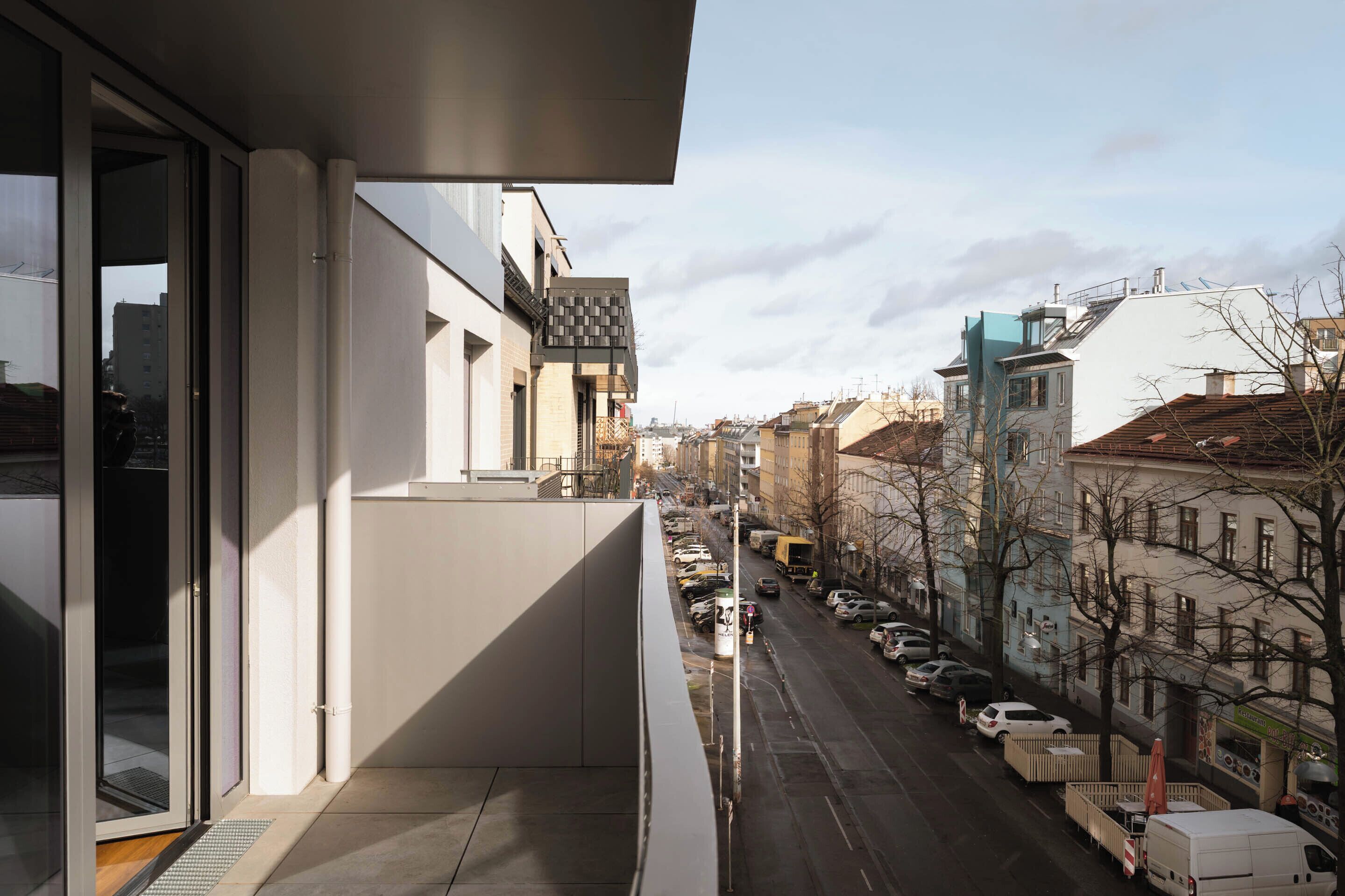 A modern building with a balcony overlooking a city street.