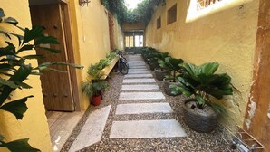 A narrow alleyway with a stone pathway, potted plants, and a bicycle parked at the end. - Cozy apartment historic center Cartagena Colombia (Cartagena de Indias)