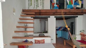 A loft-style room with a wooden staircase, a hammock, and a view of the kitchen and living area. - Cozy apartment historic center Cartagena Colombia (Cartagena de Indias)
