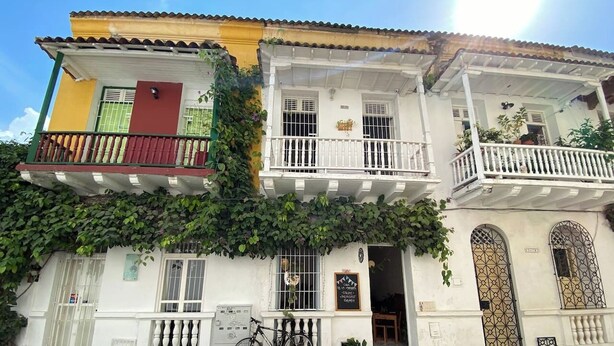 A two-story building with balconies, a bicycle parked in front, and a sign indicating a business. - Cozy apartment historic center Cartagena Colombia (Cartagena de Indias)