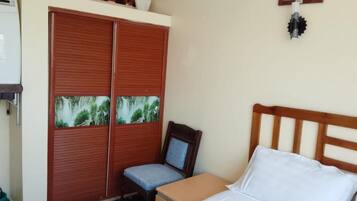A bedroom with a bed, a wooden headboard, a wardrobe with a view of a forest, a chair, and a small table.