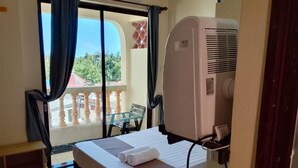 A hotel room with a bed, a window with curtains, a balcony, and a wall-mounted air conditioner. - Darad Diani Hotel (Diani Beach)