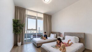 Une chambre d’hôtel avec deux lits, une grande fenêtre, une plante en pot et une vue sur la ville.