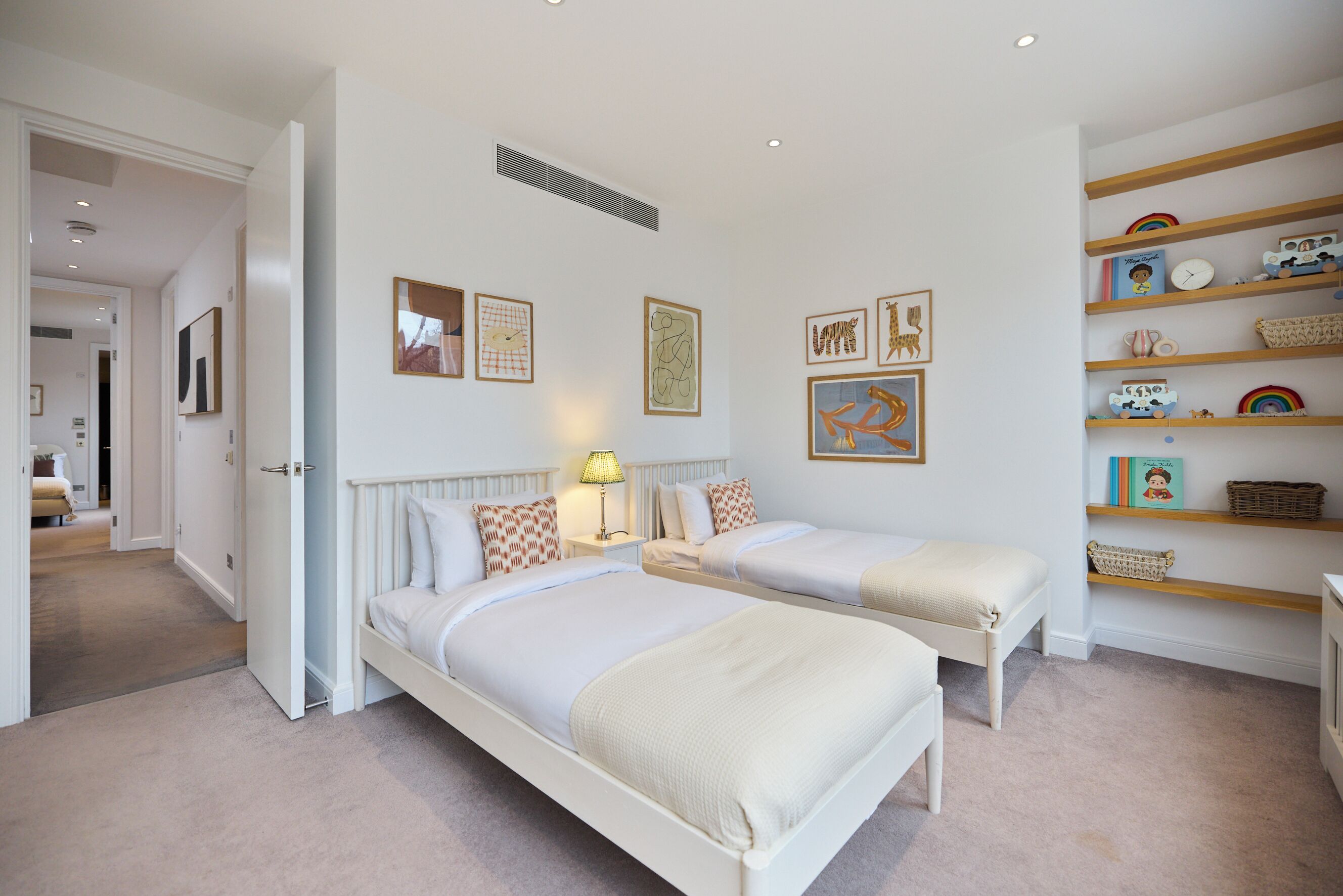 Une chambre avec deux lits, une table de chevet avec une lampe et des œuvres d’art murales.