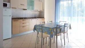A kitchen with a dining table and chairs, a microwave, and cabinets.
