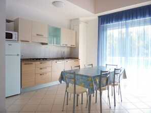 Eine Küche mit Esstisch, Stühlen, Mikrowelle und Schränken.