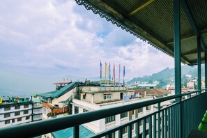 Vista desde un balcón con barandilla, que muestra un paisaje urbano con edificios y banderas.