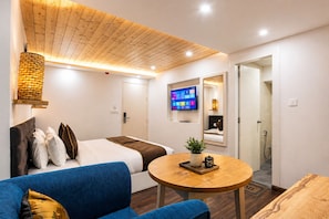 A modern hotel room with a bed, a sofa, a TV, and a small table with a plant. - Sparrow Elements Boutique Near MG Marg  (Gangtok)