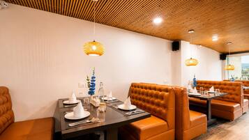 A restaurant interior with wooden ceiling, brown leather booths, and hanging wicker lamps.