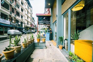 Entrada de un hotel con plantas en macetas, una recepción y un letrero que dice 'SPARROW HOTEL & RESTAURANT'.