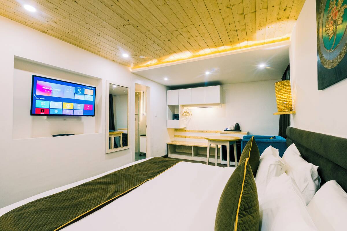 Una habitación de hotel moderna con una cama, un escritorio, un televisor y una obra de arte en la pared.