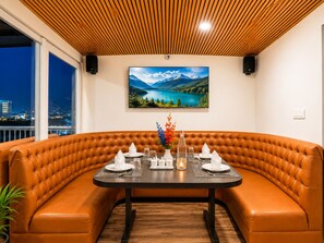 A dining area with a brown leather booth, a black table set for four, and a scenic mountain lake view. - Sparrow Elements Boutique Near MG Marg  (Gangtok)