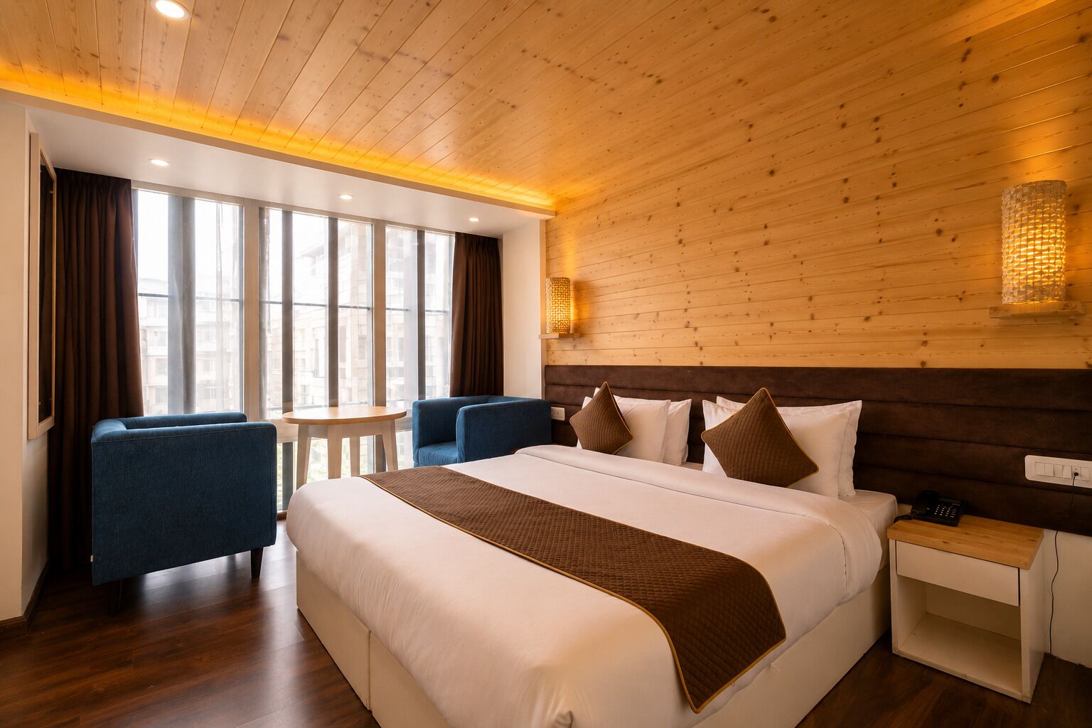 Ett hotellrum med en stor säng, ett skrivbord, en stol och ett litet bord.