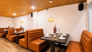 Un restaurante con cabinas de cuero, techo de madera e iluminación colgante.