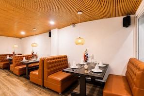 A restaurant with leather booths, wooden ceiling, and pendant lighting. - Sparrow Elements Boutique Near MG Marg  (Gangtok)