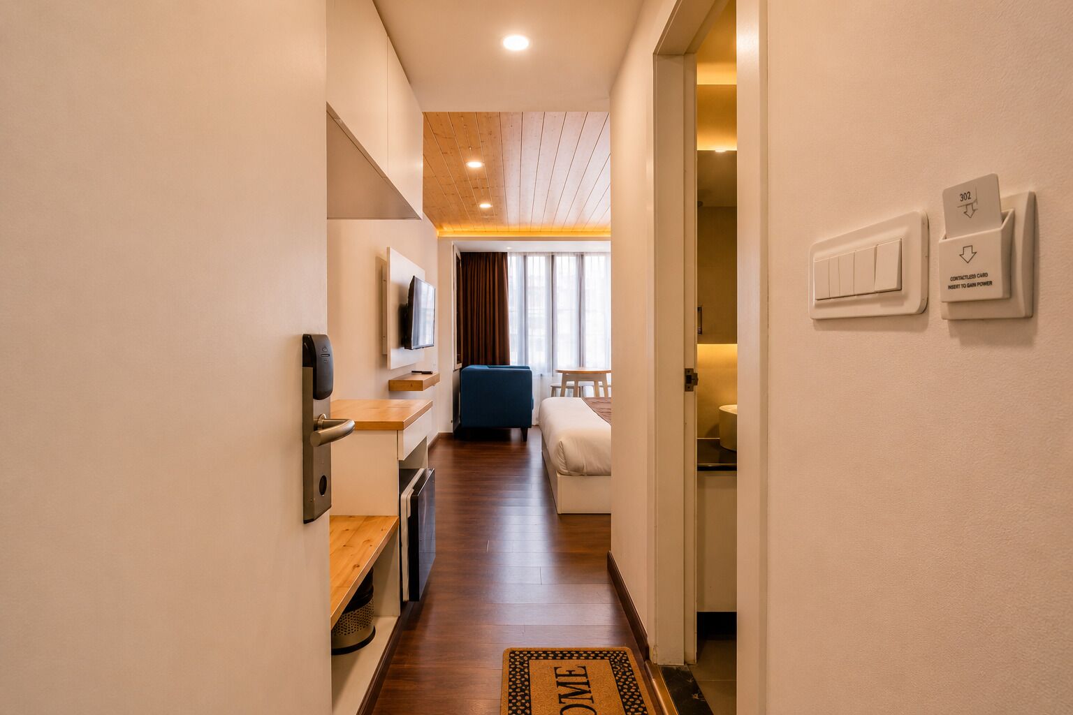 Corridoio di un hotel con un letto, una TV e una scrivania.
